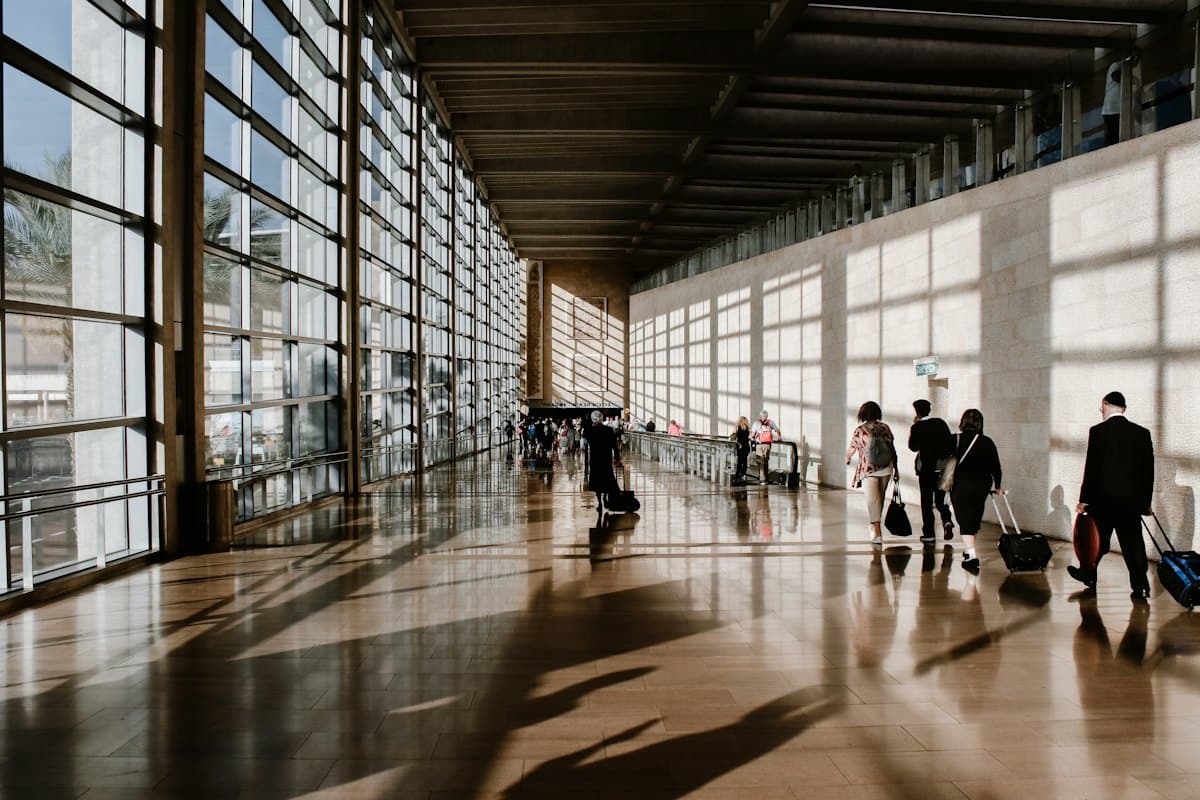 Travellers walking through a sunlit airport terminal
